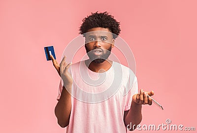 Confused black man holding credit card and cellphone Stock Photo