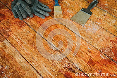 Safety gloves with paint brush and scrape tool placed on old wooden floor Stock Photo