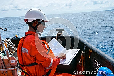 Safety officer, standing on an industrial ship, wearing overalls, a helmet, safety goggles and holding a clipboard with checklists Stock Photo