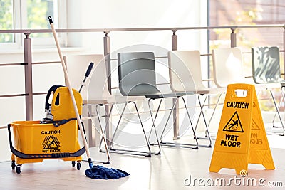 Safety sign with phrase Caution wet floor and mop bucket, indoors Stock Photo