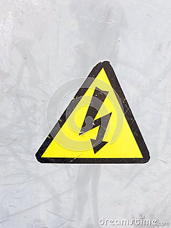 a safety sign yellow and black on silver metal background electric bolt in triangle safety caution careful Stock Photo