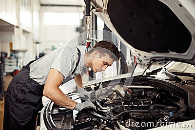 Safety sirst: a good-looking car mechanic is checking the engine Stock Photo