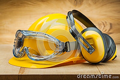 Safety of work. construction safety tools. yellow helmet blue goggles and earphones on wood background Stock Photo