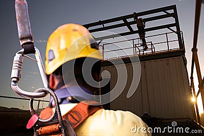 Safety workplace construction worker wearing yellow safety helmet fall arrest PPE harness attached an inertia reel shock absorber Stock Photo