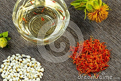 Safflower. Oil, seeds, bud, flower, red inflorescences of wild saffron. Close-up, gray fabric background. Ingredients for health, Stock Photo