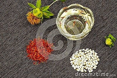 Safflower. Oil, seeds, bud, flower, red inflorescences of wild saffron. Close-up, Gray woven background. Ingredients for health, Stock Photo