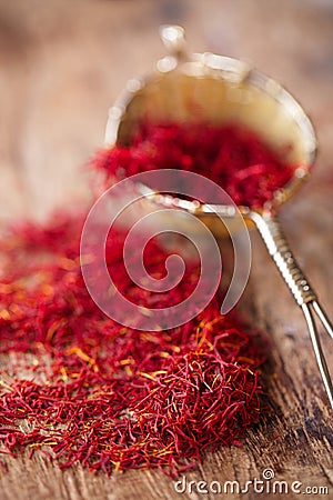 Saffron spice in rustic sieve on old wooden background Stock Photo