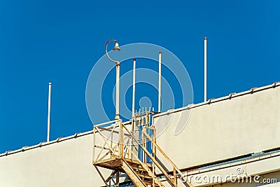 Saftey access ladder on side of building or parking structure in downtown urban city with poles and surveilance camera Stock Photo