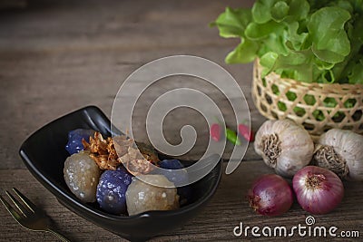 Sago pork in black plate with fried garlic toping have chilli ,Shallot, garlic, lettuce basket place right hand and gold fork Stock Photo