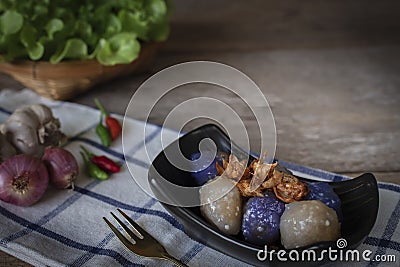 Sago pork in black plate with fried garlic toping have chilli ,Shallot, garlic place left hand and lettuce basket place backside Stock Photo