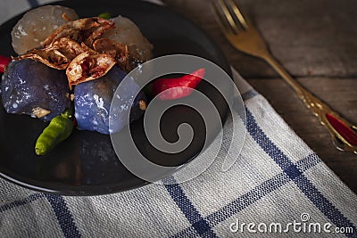 Sago pork in circle black plate with fried garlic toping have chilli place on black plate and gold fork place right hand on Stock Photo