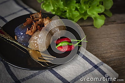 Sago pork in circle black plate with fried garlic toping have lettuce place backside and gold fork place on black plate and chilli Stock Photo
