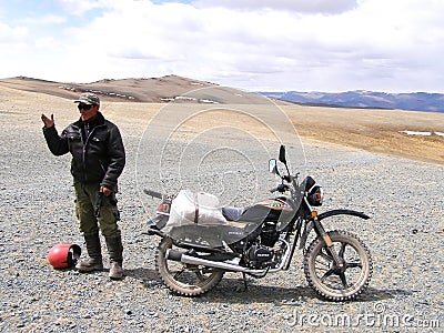 SAGSAY, MONGOLIA - MAY 22, 2012: Portrait native of Mongolian man who carry meal on his motorcycle to home in desert mountain Editorial Stock Photo