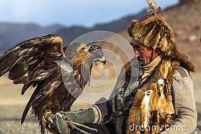 Berkutchi Eagle Hunter with golden eagle during hare hunting, in desert mountains of Western Mongolia. Editorial Stock Photo