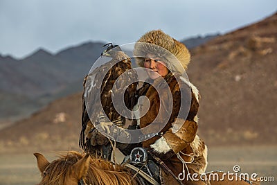 Golden Eagle Hunter teaches her young daughter hunting with birds of prey to the hare in desert mountain of Western Mongolia. Editorial Stock Photo