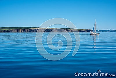 A sailboat in calm water along the coast of Newfoundland. Stock Photo