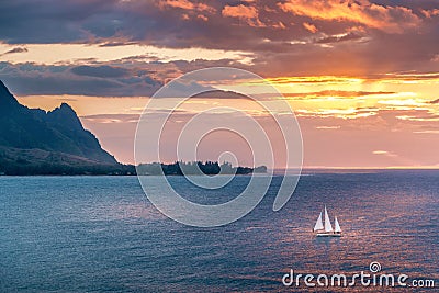 Sailboat crosses sunset on Kauai island coast Stock Photo