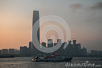 Sailboat gliding through the water in front of a vibrant cityscape, illuminated by the setting sun Stock Photo