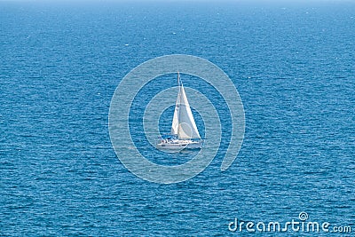 Sailboat sailing alone in vast blue Gulf of Mexico off the coast of Panama City Beach Florida Stock Photo