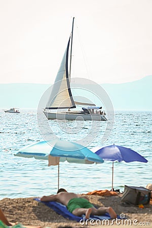 Sailboat sails next to the beach Stock Photo