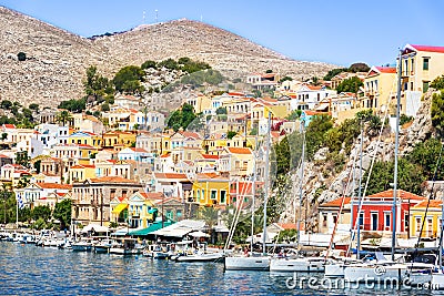 Sailboats and colorful neoclassical houses in harbor town of Symi Symi Island, Greece Stock Photo