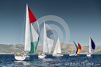 Sailboats compete in a sail regatta at sunset, race of sailboats, reflection of sails on water, multicolored spinnakers Stock Photo