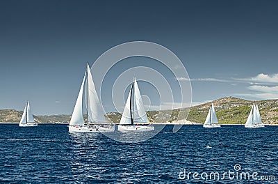 Sailboats compete in a sail regatta at sunset, race of sailboats, reflection of sails on water, multicolored spinnakers Stock Photo