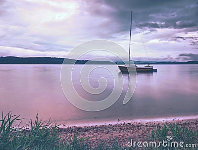 Sailing boat anchoring next to a buoy in the calm water of lake Stock Photo