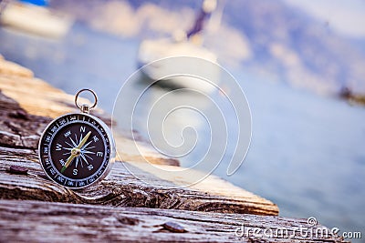 Sailing: nautical compass on wooden dock pier. Sailing boats in the background Stock Photo