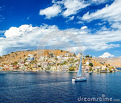 Sailing yacht in the beautiful buildings of Symi island, Greece, clouds, sky, bright Sunny day Editorial Stock Photo