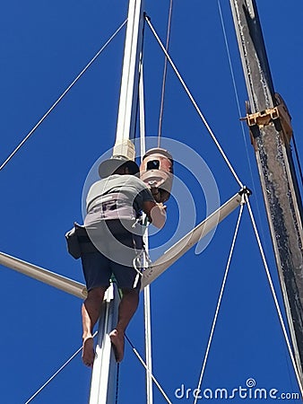 A sailor climbing up to fix the sail boat mast in Kudat, Malaysia. Stock Photo