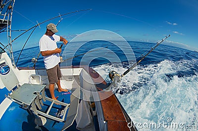 Sailor gets ready reels and rods for marlin game fishing at sea near Saint-Denis, Reunion island. Editorial Stock Photo