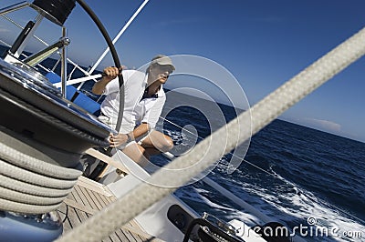 Sailor At Helm of Sailboat Stock Photo