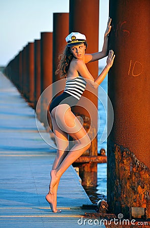 Sailor model in stylish swimsuit and captain hat posing on the wooden pier Stock Photo