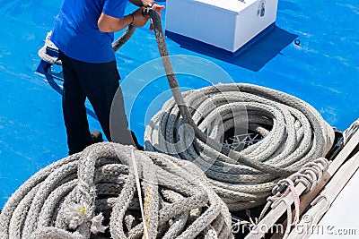 Sailor on the ship is giving mooring in the port. The rope is coiling and wounding in a spiral Stock Photo