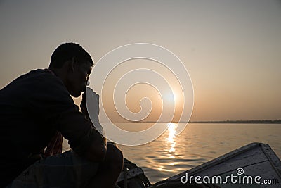 A sailor sits on a boat looking at the sunset. Editorial Stock Photo