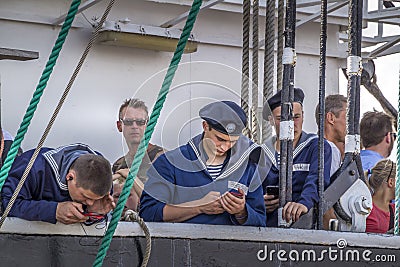 Sailors are busy checking the cell phone. Tall Ships Races in Esbjerg harbor Editorial Stock Photo