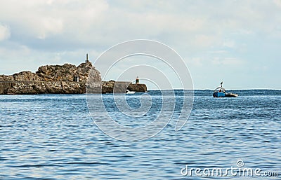 Sailors working on a boat in the water with the horizon line in the background on a cloudy day with blue sky and lighthouses Stock Photo