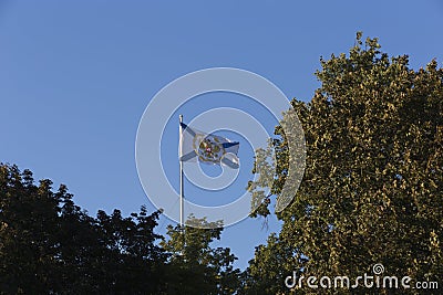 Saint Andrew Andreevsky flag Ensign of the Russian Navy on a flagpole waving the roof of the Admiralty building behind trees Stock Photo