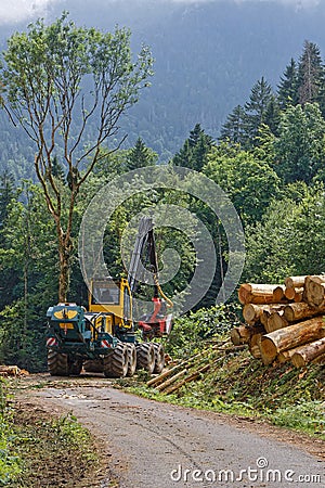 A huge tractor works in the forests of the slopes of Belledonne mountain range Editorial Stock Photo