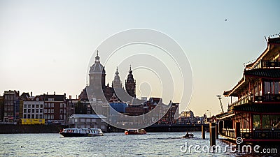 Saint Nicholas Basilica the major Catholic church in Old center District and typical Dutch houses and tour boats, Amsterdam, The Editorial Stock Photo