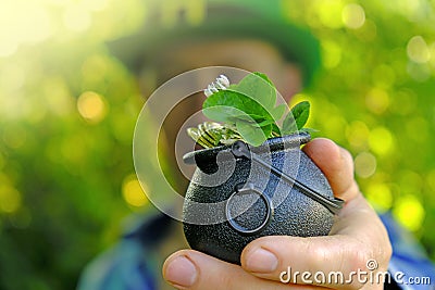 Saint Patrick .clover leaf in bowler hat with gold coins in the hand of a man in a green hat in a sunny garden.Four-leaf Stock Photo