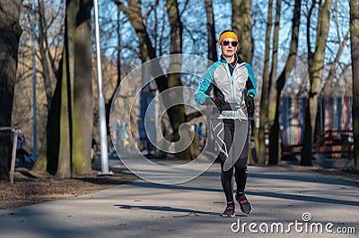 Saint-Petersburg, Russia, 19.04.2021 An adult woman in a tracksuit runs on a treadmill in the park. Editorial Stock Photo