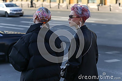 Two young fashionable girls walk along a street in the center of the city Editorial Stock Photo