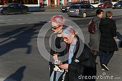 Two young fashionable girls walk along a street in the center of the city Editorial Stock Photo