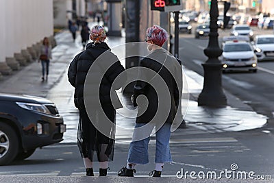 Two young fashionable girls walk along a street in the center of the city Editorial Stock Photo