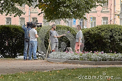 Saint-Petersburg, Russia - 9 August 2019: Professional cameraman and journalist interviews a girl in the city center Editorial Stock Photo