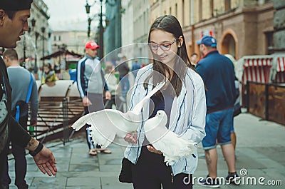 Girl teenager walks on the street of St. Petersburg, holds in the hands of white pigeons Editorial Stock Photo