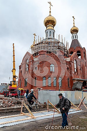 People bypass the fallen fence enclosing the construction of an Orthodox church Editorial Stock Photo