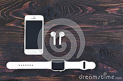 White smartphone iPhone 5S+, smartwatch Apple watch sport with a band and wireless headphones Airpods on the background Editorial Stock Photo